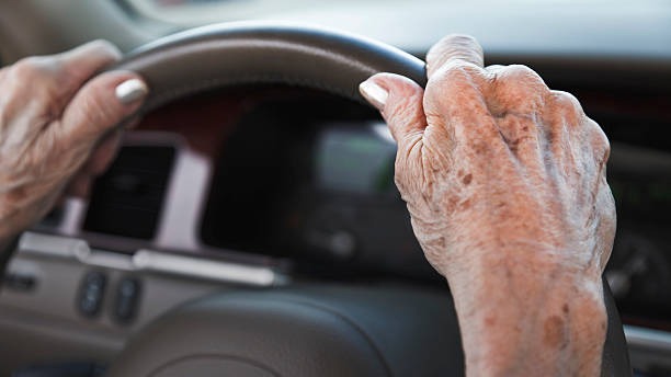 Mains d'une personne âgée qui tiennent un volant