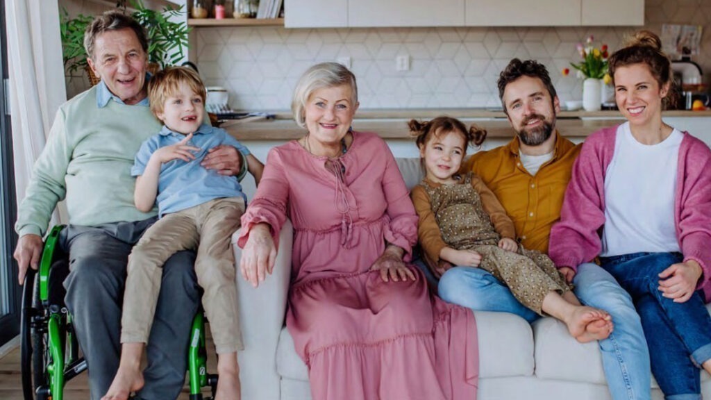 A happy family photo of parents with young children and grandparents. One of them on wheelchair.